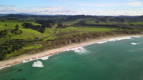 Aerial-view-of-Hahei,-Hot-water-beach-in-the-Coromandel-with-rolling-farm-land-hills-behind
