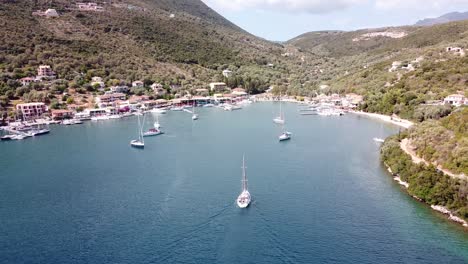 Luxury-Boat-Sails-to-Port-at-Mikros-Gialos,-Lefkada,-Greece---Aerial-Follow