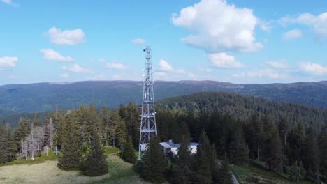 Aerial-orbit-view-around-a-tall-telecommunication-antenna-mast-pylon-among-mountain-forest-in-Sérichamp-Vosges-France-4K