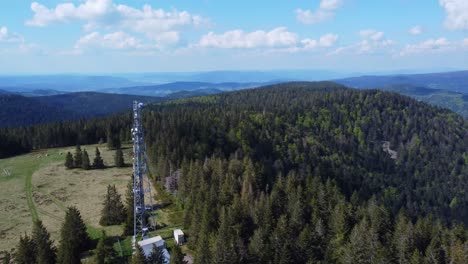 Aerial-fly-along-a-tall-telecommunication-antenna-mast-pylon-among-mountain-forest-in-Sérichamp-Vosges-France-4K