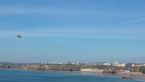 Coastguard-Search-and-Rescue-Helicopter-Flying-Over-Newquay-Bay-and-Towan-Beach-in-Distance,-Cornwall,-UK---wide