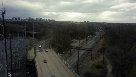 Railroad-Track-Underneath-Highway-Bridge-Full-Of-Cars,-Drone-Tracking-Shot