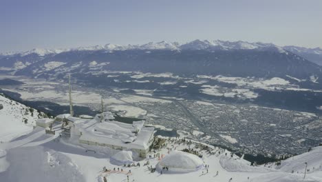 Nordkette-ski-resort-drone-reveal-with-Innsbruck-aerial-cityscape,-bird's-eye-view,-drone-flyover-Austrian-Alps