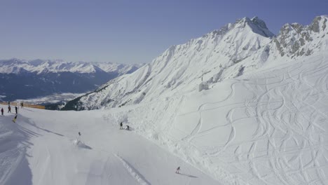 Austrian-Alps-drone-reveal-into-Nordkette-ski-resort-above-Innsbruck,-Skyline-terrain-park-skier-going-off-jump-at-ski-resort