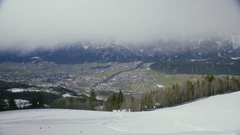 Wide-Innsbruck-view-from-foothills-with-foggy-mountains-and-hiker