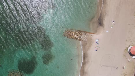 Aerial-view-over-a-quiet-beach-and-transparent,-shallow-water-in-St-Kitts---overhead,-drone-shot