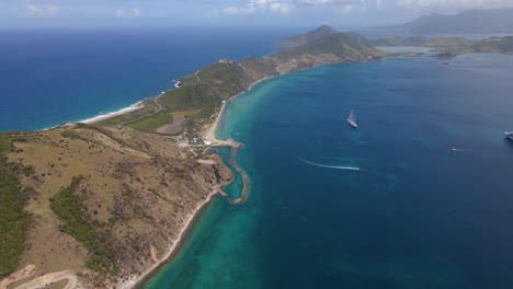 Aerial-view-of-a-sailboat-and-a-cruise-ship-on-the-coastline-of-Saint-Kitts-and-Nevis---pan,-drone-shot