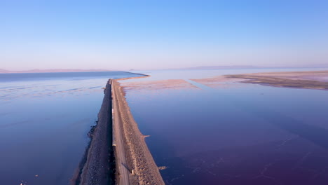 Drone-flying-over-cargo-train-crossing-the-railroad-causeway-of-the-Great-Salt-Lake,-Utah