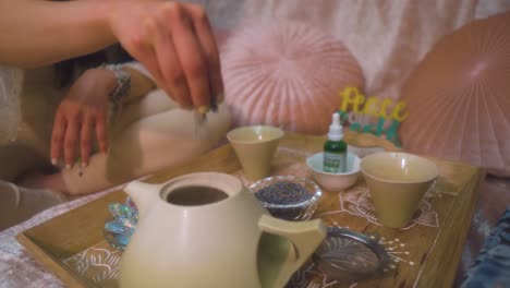 Spiritual-healer-is-putting-herbs-into-the-tea-pot-to-heal-her-client-with-the-natural-ingridenece-in-peaceful-environment