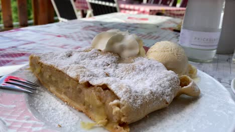 Delicous-apple-strudel-with-ice-cream-on-a-plate-with-sugar,-a-very-famous-austrian-delicacy