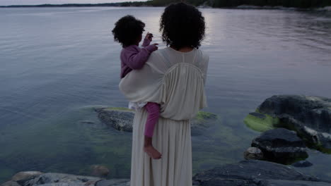 Mother-holding-daughter-nurturing-care-watching-lake-water-together-family-bonding-bond-parent-parenting-loving-love-nature-lake-beach-hold-child-sunset-calming-relaxing-view-nurture-motherhood-woman