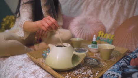 spiritual-woman-preparing-tea-using-a-feather-and-natural-herbs-for-healing