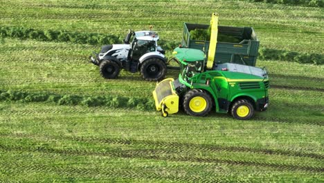 Aerial-Tracking-Shot-Of-Freshly-Cut-Silage-Being-Offloaded-Onto-A-Truck