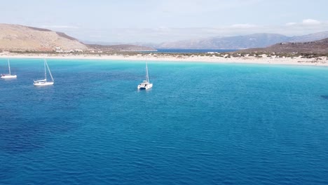 Barcos-De-Lujo-En-La-Bahía-Turquesa-En-La-Isla-De-Elafonisos,-Peloponeso,-Grecia---Antena
