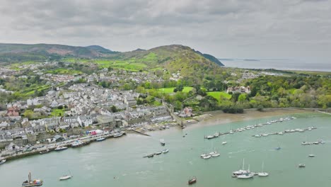 A-large-number-of-sailboats-and-motor-vessels-are-moored-at-the-long-jetty-in-the-fast-flowing-river-off-the-English-town-of-Conwy-among-the-green-hills-of-Wales-on-a-cloudy-day