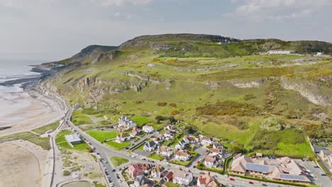 Residential-area-with-huge-villas-on-Conwy-Bay-with-beautiful-views-of-the-sea-during-low-tide-and-the-high-green-hills-in-the-background-on-a-cloudy-day