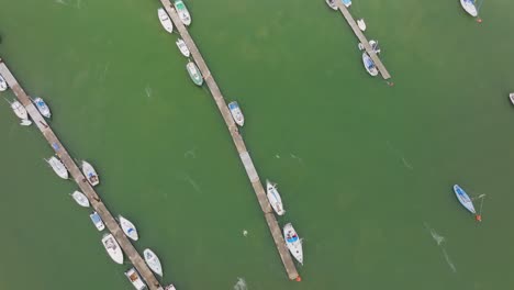 several-sailing-yachts-and-motor-boats-are-moored-to-the-long-wooden-jetties-in-the-green-colored-fast-flowing-sea-water-in-Wales-on-a-sunny-day