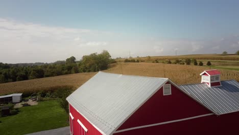 Antenne-Eines-Roten-Bauernhauses-In-Der-Ländlichen-Gegend-Von-Pennsylvania,-Umgeben-Von-Maisfeldern-Und-Bäumen