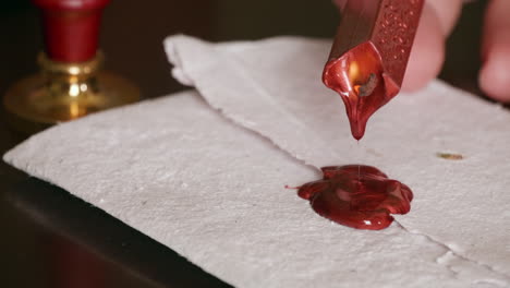 Hot-wax-drips-on-a-piece-of-parchment-in-preparation-for-a-wax-seal