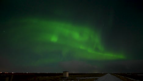 Man-watching-beautiful-green-Northern-Polar-Lights-at-dark-sky-in-Iceland---Silhouette-of-person-outdoors-at-night---wide-shot