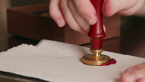 Pressing-a-wax-seal-into-hot-wax-on-a-piece-of-parchment,-sealing-the-letter