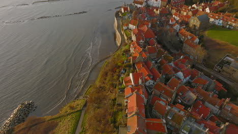 North-York-Moors-Heritage-Coast,-Robin-Hoods-Bay,-Aerial-drone-flight-over-RHB-village-early-morning-pull-back-from-slipway-then-pan-up-reveal-DJI-Mavic-3-Cine-Prores-422-March-2022-Clip-2