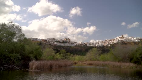 Slow-motion-pan-across-pond-with-whitewashed-Mediterranean-city-up-on-hill