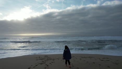 Young-Girl-on-the-Beach-at-Winter-Day-with-Storm-Clouds-in-the-Sky