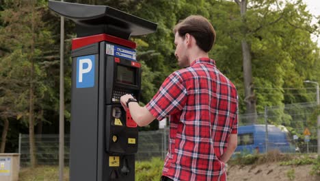 Young-man-use-parking-meter-to-pay-for-car-parking