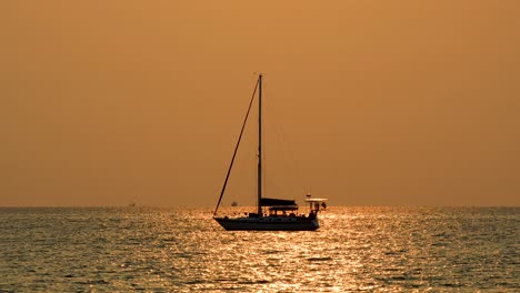 Yacht-on-the-Horizon-with-Orange-Glow-Sunset-in-Bangsaray-near-Pattaya,-Thailand