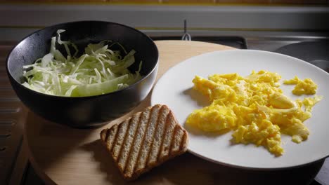 Scrambled-Eggs,-Bowl-With-Sliced-Cabbage-and-Toast-Presented-on-Table