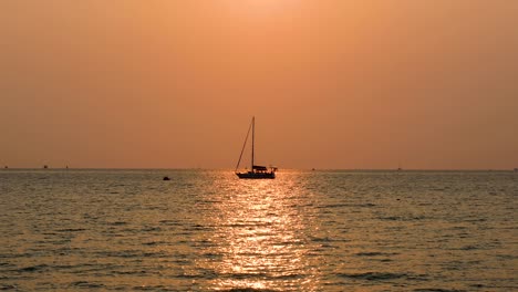 Ein-Ruhiger-Sonnenuntergang-Mit-Einer-Yacht-Am-Horizont-Mit-Orangefarbenen-Und-Rosafarbenen-Himmeln-Entlang-Des-Ozeanhorizonts-In-Bangsaray-Bei-Pattaya,-Thailand