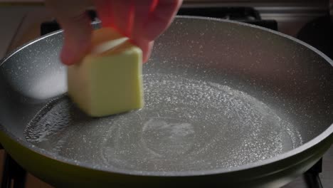 Close-up-view-of-hand-greasing-a-pan-using-butter,-Adding-butter-to-pan