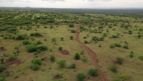 Savanna-dirt-road,-idyllic-African-landscape-with-Kilimanjaro-in-distance,-Kenya