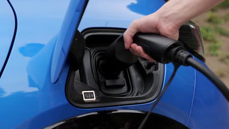 Plugging-in-charge-connector-to-electric-car,-renewable-energy