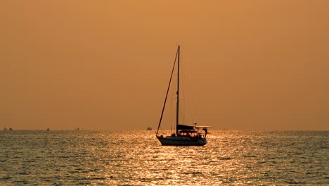 Schöne-Silhouette-Einer-Yacht-Mit-Orange-Leuchtendem-Sonnenuntergang-Im-Hintergrund-Mit-Reflexionen-Auf-Dem-Ozeanwasser-Von-Bangsaray-In-Der-Nähe-Von-Pattaya,-Thaland