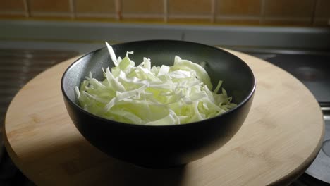 Person-pours-sliced-cabbage-into-a-bowl,-cooking-delicious-scrambled-eggs