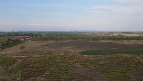 Aerial-footage-towards-the-horizon-over-grasslands-and-farmlands-in-Pak-Pli,-Nakorn-Nayok,-Thailand