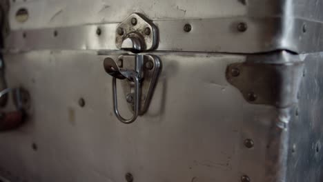 A-man's-hand-opens-the-latch-on-a-sturdy-silver-trunk