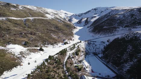 Aerial-view-of-people-skiing-down-slopes-of-Sierra-Nevada-ski-resort,-Spain