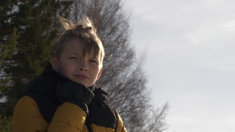 young-boy-wearing-winter-coat-outdoors-looking-at-a-distant-as-wind-blows