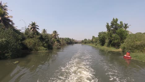 Vista-De-Barco-Navegue-A-Lo-Largo-De-Un-Canal-Tradicional-Con-Vegetación-Exuberante-En-El-Distrito-De-Alappuzha,-Kerala
