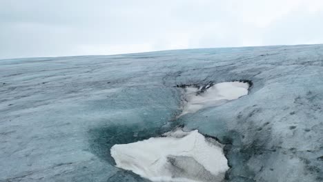 Rückwärtsaufnahme-Aus-Der-Luft-Des-Gletscherauslasses-Breiðamerkurjökull-Und-Eishöhlen-Darunter---In-Der-Nähe-Von-Jökulsárlón,-Island