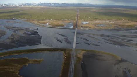 Descending-aerial-view-of-car-driving-on-bridge-over-Eldvatn-River-in-Iceland---Cinematic-panorama-shot-of-scenic-landscape-in-Iceland