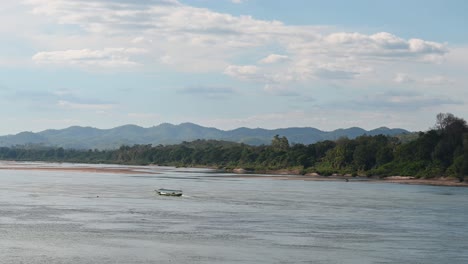 A-touring-boat-fighting-the-current-to-get-to-destination-navigating-Mekong-River,-Thailand-and-Laos