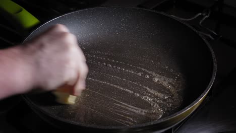 Greasing-Hot-Cast-Iron-Pan-With-Butter-Before-Pouring-Eggs-For-Frying