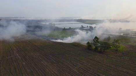 Steady-aerial-footage-of-a-smoking-farmland-in-Pak-Pli,-Nakhon-Nayok,-Thailand