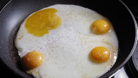 Braten-Von-Eiern-In-Einer-Pfanne,-Gewürzt-Mit-Salz-Und-Pfeffer