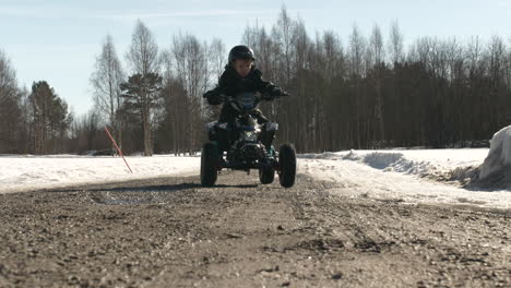 Kaukasischer-Junge,-Der-Mini-ATV-Auf-Unbefestigter-Straße-Im-Schnee-Fährt