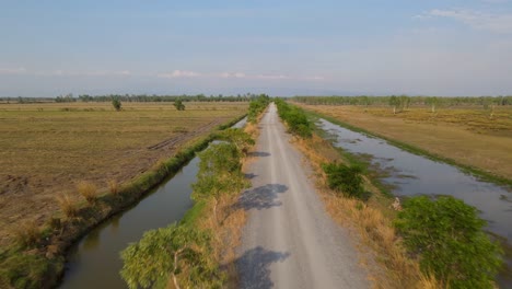 Aerial-footage-over-a-farm-road-towaards-a-the-horizon,-Pak-Pli,-Nakorn-Nayok,-Thailand